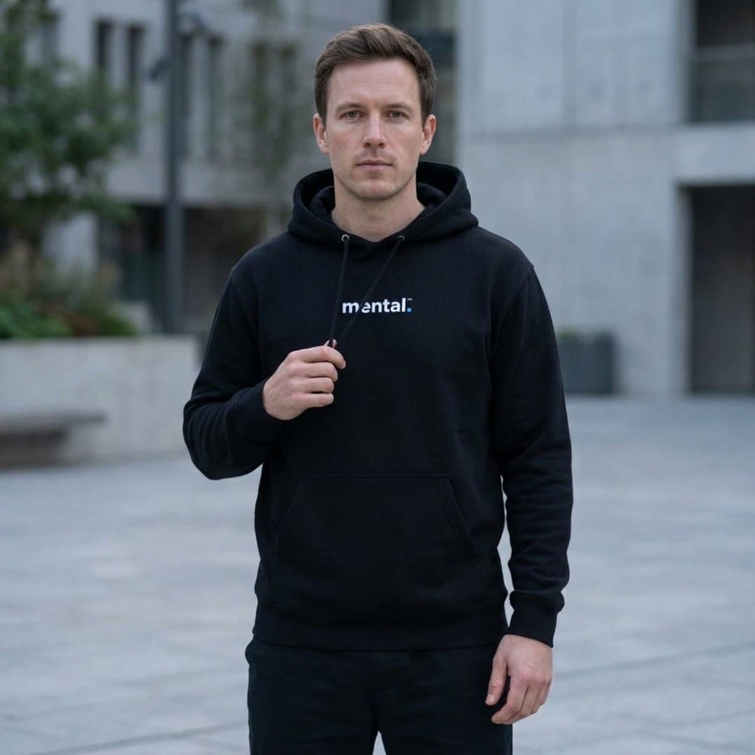 Man wearing black hoodie with 'mental.' slogan outdoors