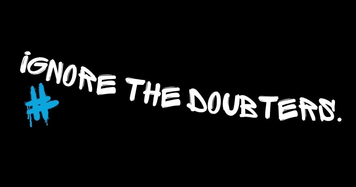 ignore the doubters White graffiti slogan 'Ignore the doubters' with blue hashtag